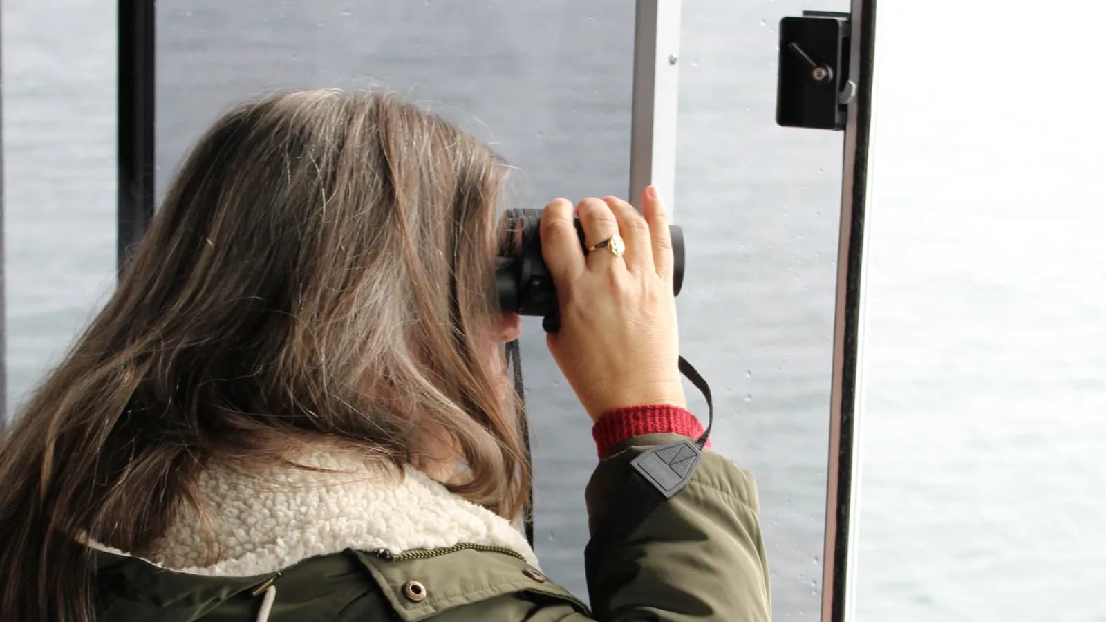 Guest using binoculars during an Alaska whale watching tour